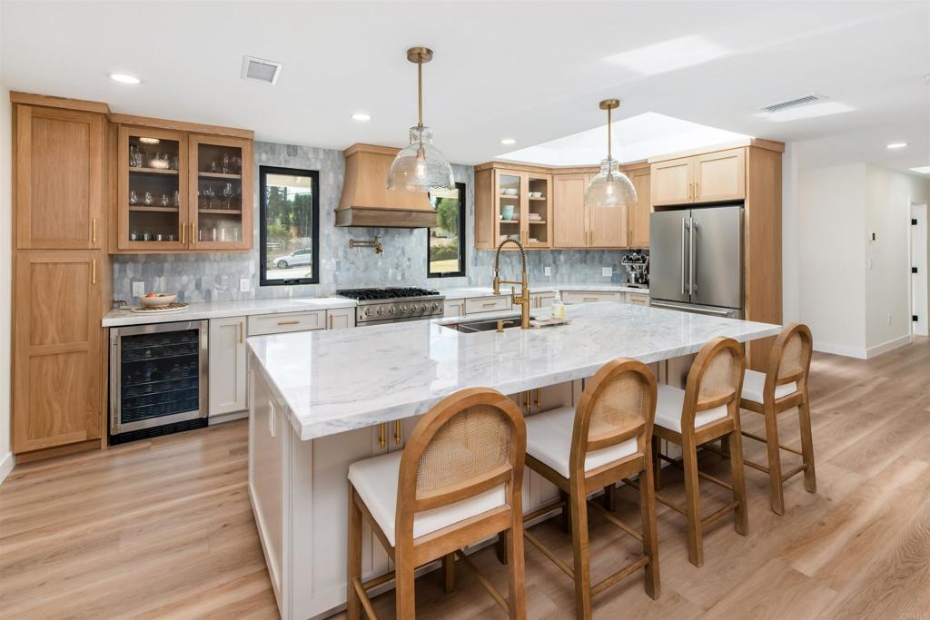 kitchen featuring wine cooler, sink, custom exhaust hood, high quality appliances, and an island with sink