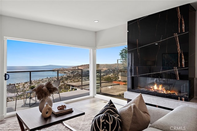 living room featuring a tile fireplace, a water view, and wood-type flooring