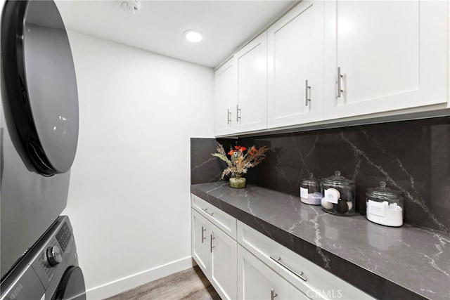 bar featuring tasteful backsplash, stacked washer and dryer, light hardwood / wood-style floors, and white cabinets