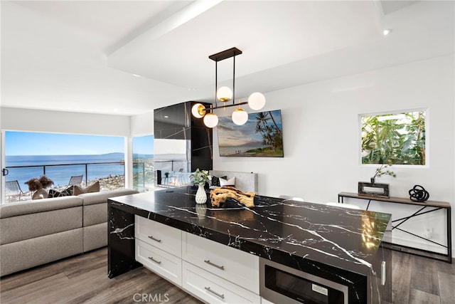 kitchen with hanging light fixtures, white cabinetry, a water view, and dark hardwood / wood-style floors