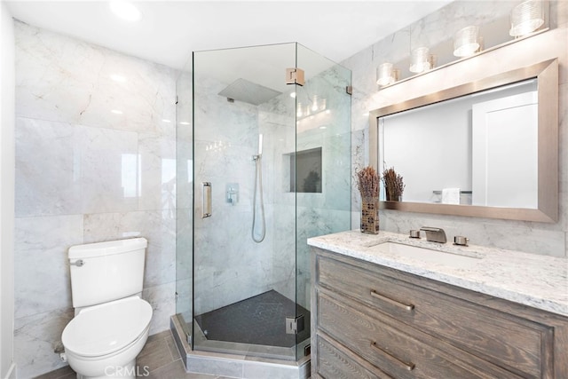 bathroom featuring vanity, a shower with shower door, tile walls, and toilet