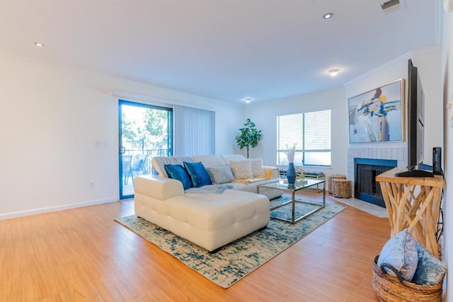 living room featuring crown molding, a fireplace, and light wood-type flooring