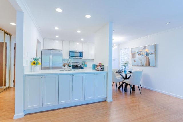 kitchen with appliances with stainless steel finishes, sink, white cabinets, ornamental molding, and light hardwood / wood-style floors