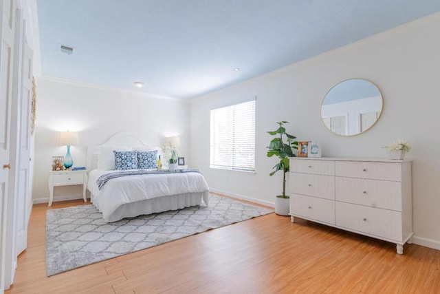 bedroom featuring ornamental molding and light hardwood / wood-style floors