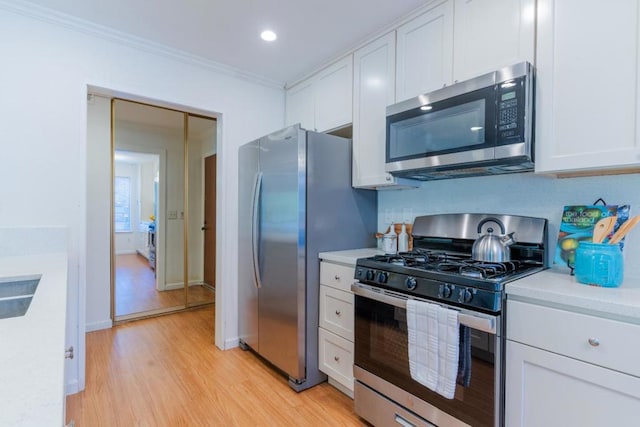 kitchen with stainless steel appliances, light hardwood / wood-style flooring, and white cabinets