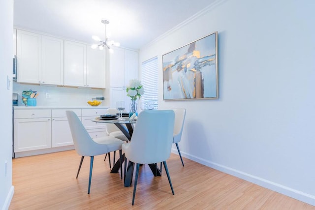 dining space with crown molding, an inviting chandelier, and light hardwood / wood-style floors