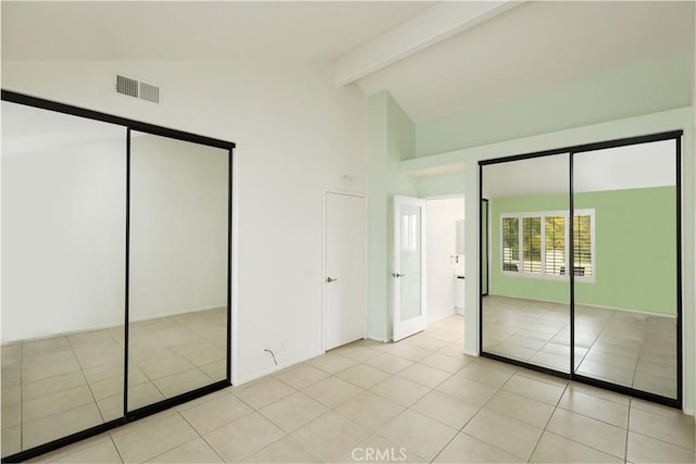 unfurnished bedroom with light tile patterned floors, high vaulted ceiling, and beamed ceiling