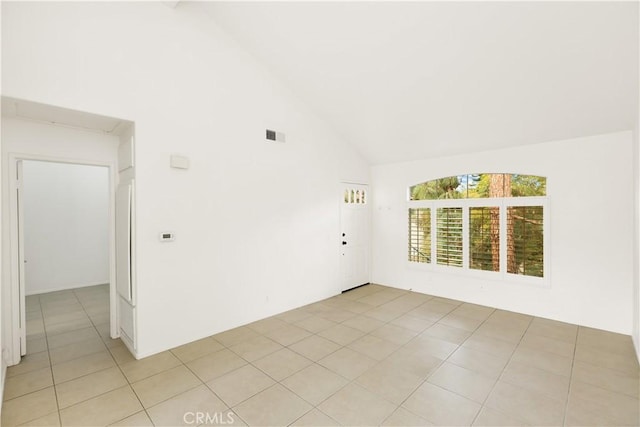 spare room with high vaulted ceiling and light tile patterned floors