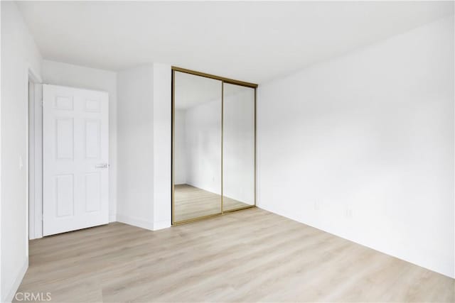 unfurnished bedroom featuring light hardwood / wood-style flooring and a closet