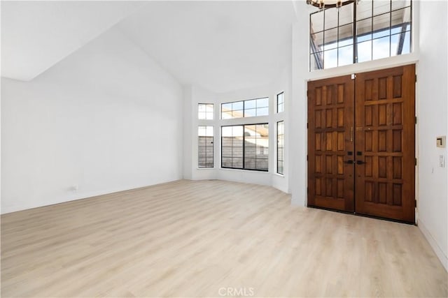 foyer entrance featuring a towering ceiling and light hardwood / wood-style flooring