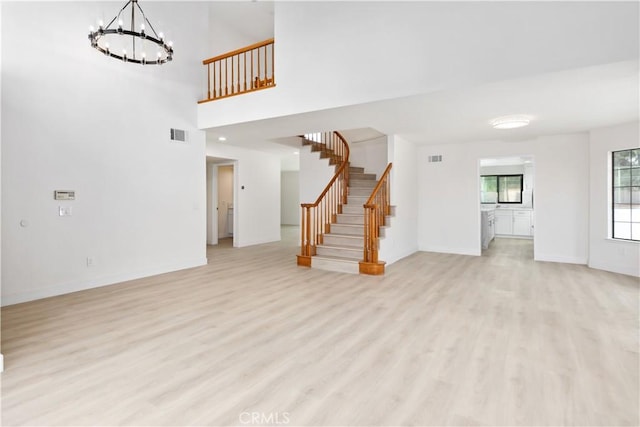 unfurnished living room with an inviting chandelier and light wood-type flooring