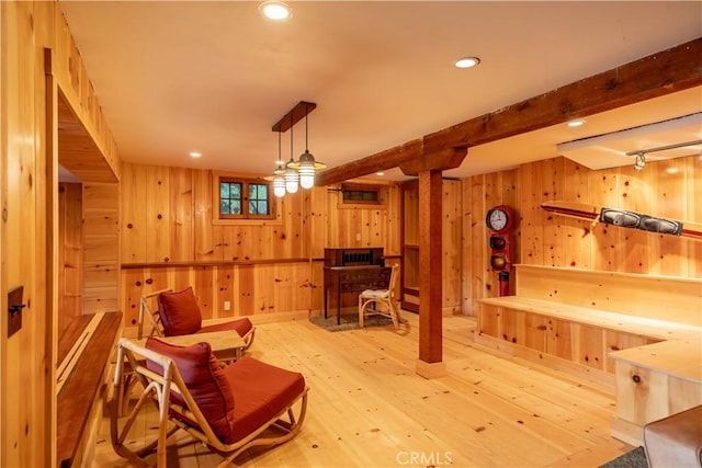 sitting room with beam ceiling, light hardwood / wood-style flooring, and wood walls