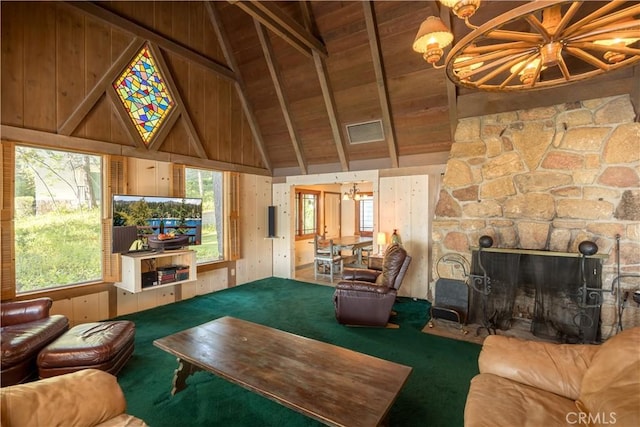 carpeted living room featuring an inviting chandelier, a healthy amount of sunlight, beam ceiling, and a stone fireplace