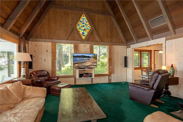 carpeted living room with beamed ceiling, a healthy amount of sunlight, wooden walls, and high vaulted ceiling