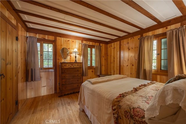 bedroom featuring multiple windows, beam ceiling, and light hardwood / wood-style floors