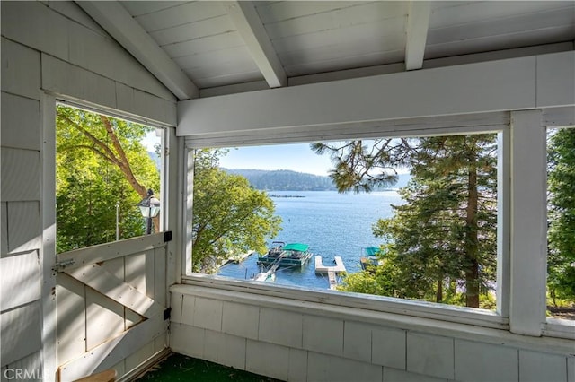 unfurnished sunroom featuring a water view and vaulted ceiling with beams