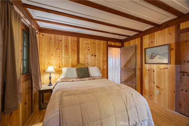 bedroom with light hardwood / wood-style flooring, beam ceiling, and wooden walls