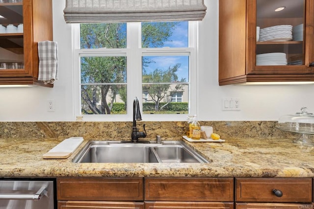 kitchen featuring dishwasher, sink, and light stone countertops