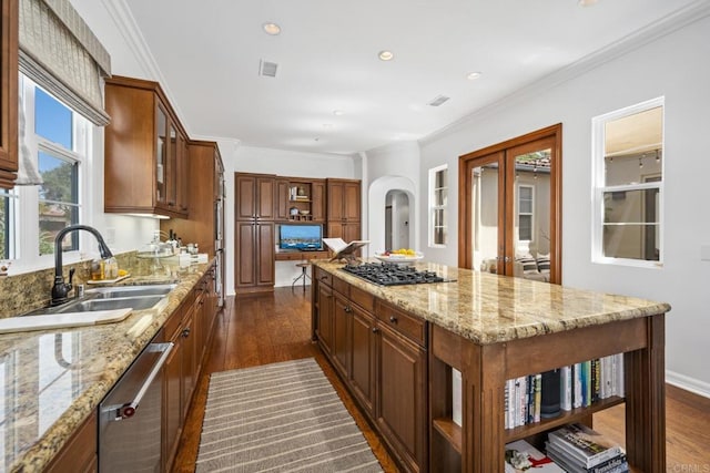 kitchen with appliances with stainless steel finishes, sink, ornamental molding, a center island, and light stone countertops