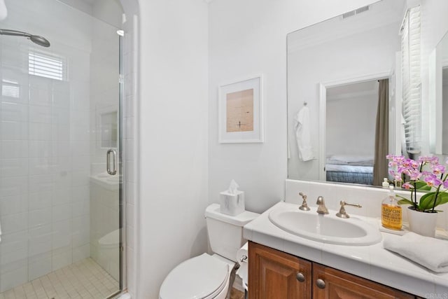 bathroom with toilet, vanity, and a shower with door