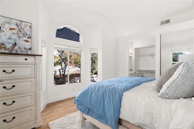 bedroom featuring lofted ceiling, a closet, and light wood-type flooring