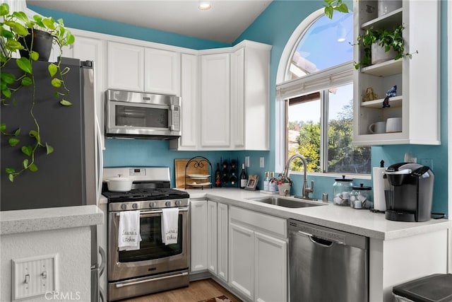 kitchen with white cabinetry, appliances with stainless steel finishes, sink, and light hardwood / wood-style flooring