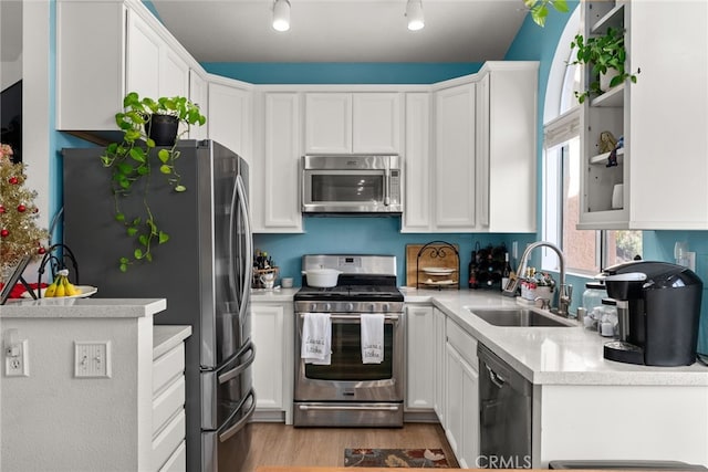 kitchen featuring stainless steel appliances, sink, white cabinets, and light hardwood / wood-style floors