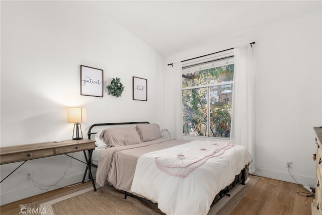 bedroom featuring hardwood / wood-style flooring and vaulted ceiling