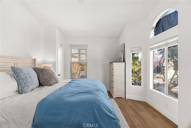 bedroom with vaulted ceiling and light hardwood / wood-style floors