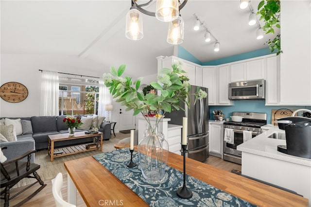 kitchen featuring sink, stainless steel appliances, light hardwood / wood-style floors, white cabinets, and vaulted ceiling