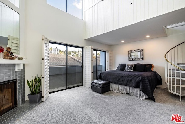 carpeted bedroom with a fireplace, a towering ceiling, and access to outside