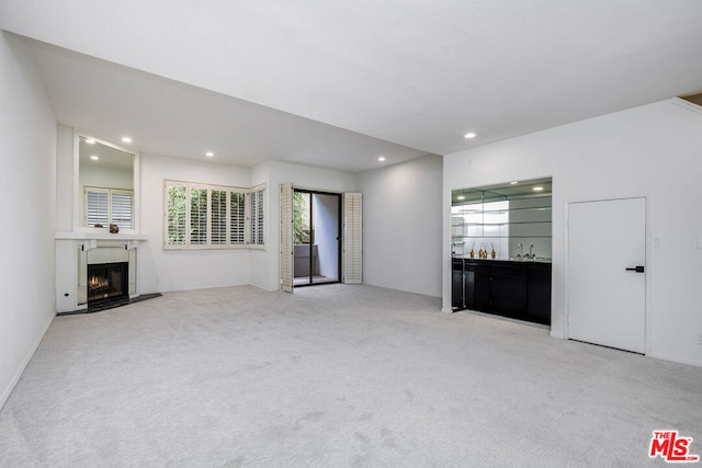 unfurnished living room with light colored carpet and indoor wet bar