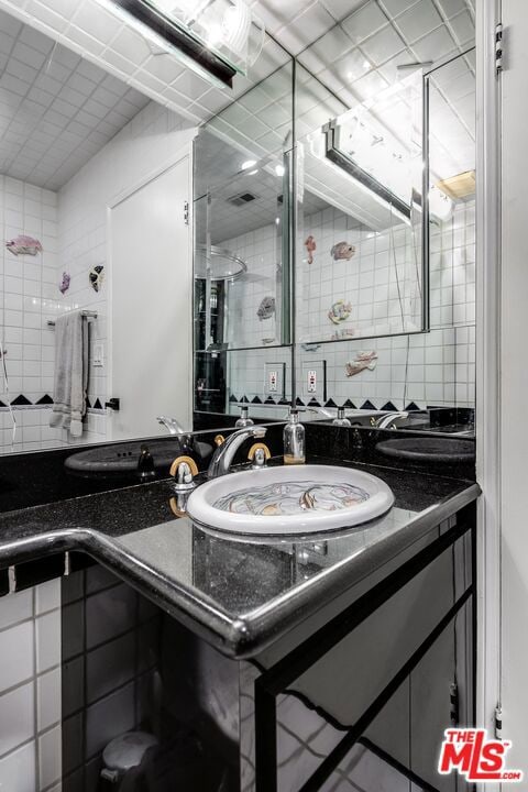 bathroom with walk in shower, vanity, and backsplash