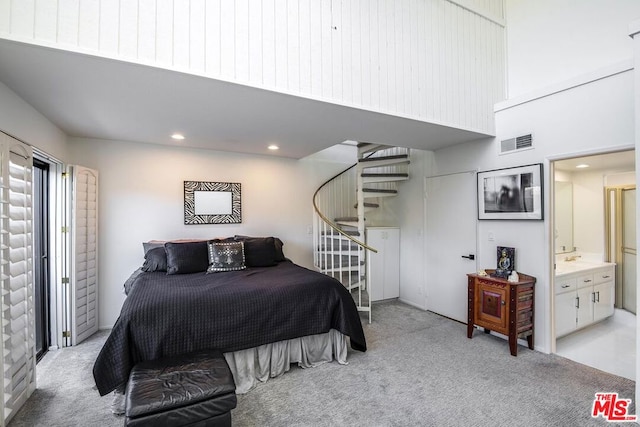 bedroom featuring connected bathroom and light colored carpet