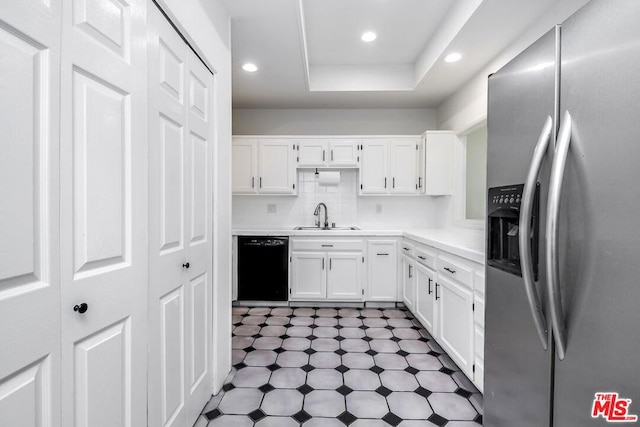 kitchen featuring black dishwasher, sink, white cabinets, stainless steel fridge, and a raised ceiling