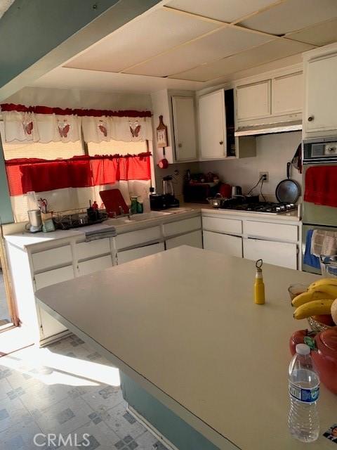 kitchen with double oven, white cabinets, black gas stovetop, and light countertops