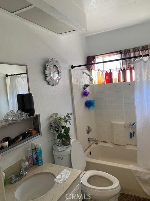 bathroom featuring toilet, vanity, and shower / bathtub combination with curtain
