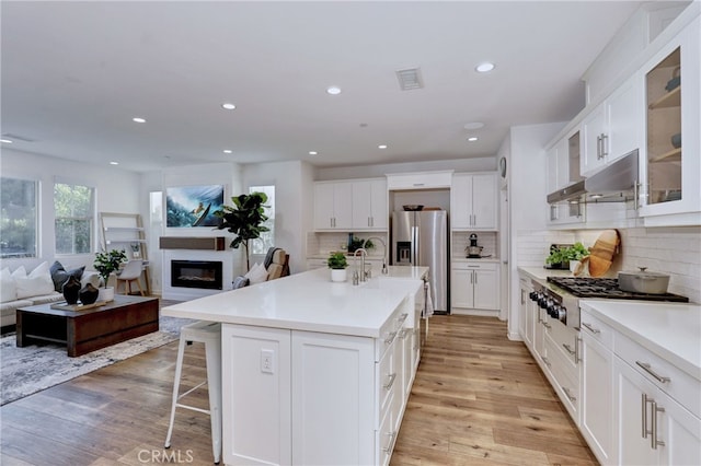 kitchen with a kitchen island with sink, white cabinets, and appliances with stainless steel finishes