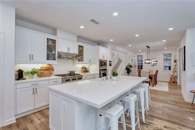 kitchen featuring appliances with stainless steel finishes, a kitchen island with sink, and white cabinets