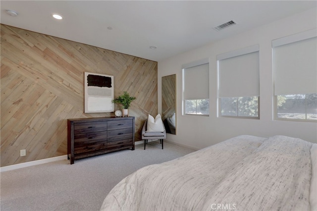 bedroom featuring light colored carpet and wooden walls