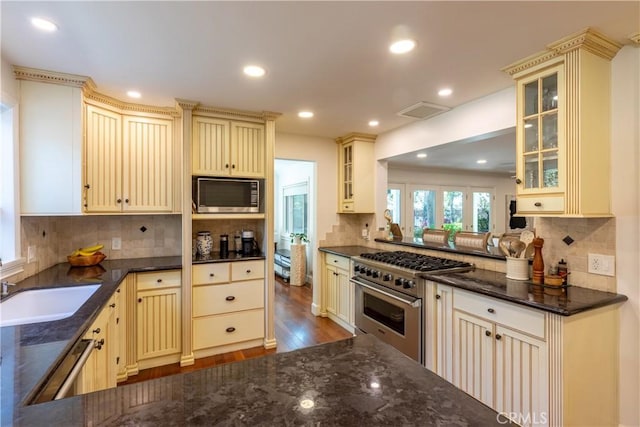 kitchen with appliances with stainless steel finishes, sink, cream cabinets, and hardwood / wood-style floors