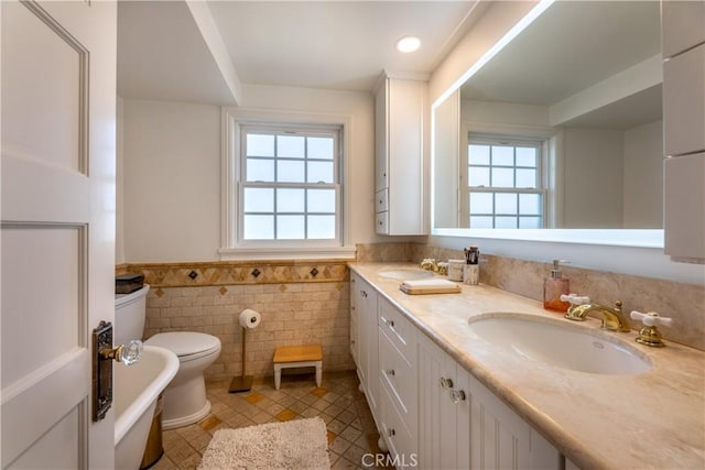 bathroom with tile walls, tile patterned flooring, a bathtub, vanity, and toilet