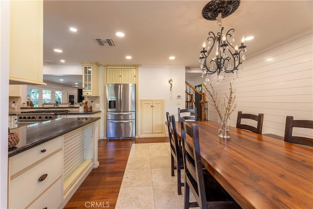 dining space featuring a notable chandelier, ornamental molding, hardwood / wood-style floors, and wood walls