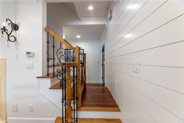 stairs with ornamental molding and hardwood / wood-style floors