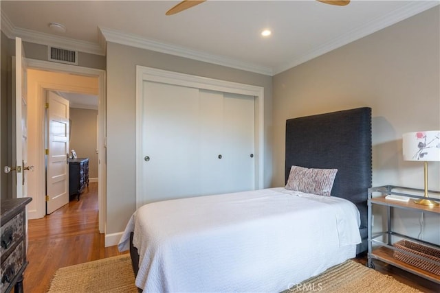 bedroom with crown molding, wood-type flooring, a closet, and ceiling fan