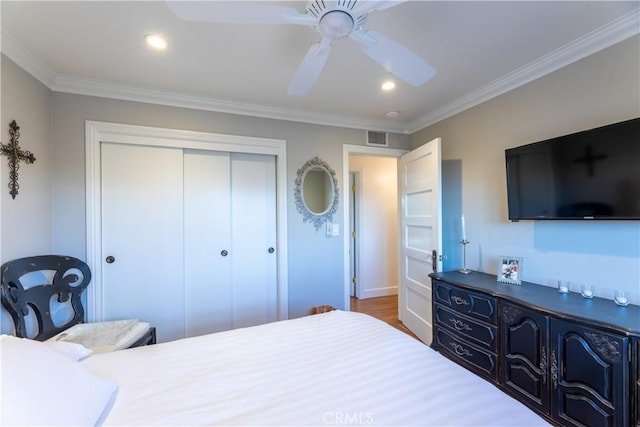 bedroom featuring ornamental molding, wood-type flooring, ceiling fan, and a closet