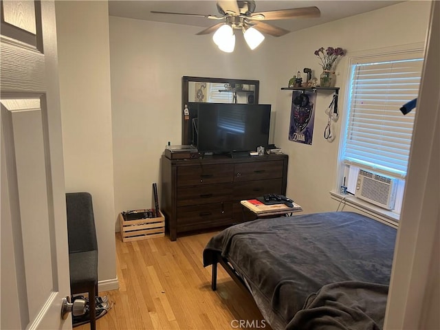 bedroom with cooling unit, ceiling fan, and light wood-type flooring