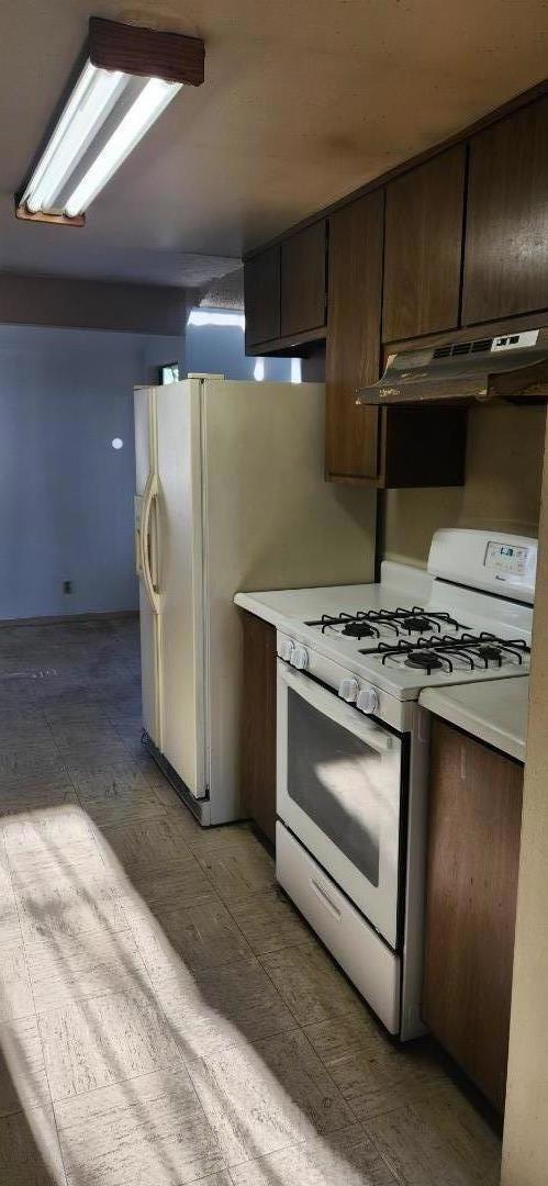 kitchen featuring white appliances and dark brown cabinets