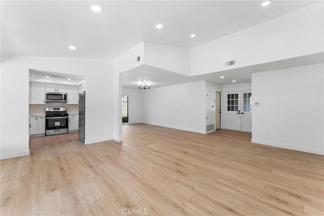 unfurnished living room featuring vaulted ceiling and light hardwood / wood-style flooring