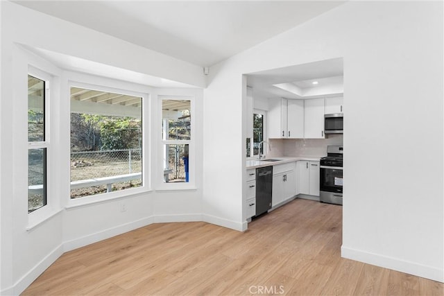 kitchen featuring stainless steel appliances, a wealth of natural light, white cabinets, and light wood-type flooring